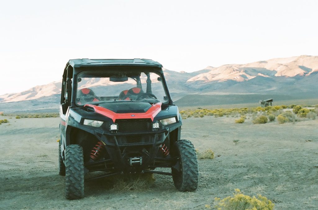 Utility terrain vehicle parked on rocky ground with mountains in the background.